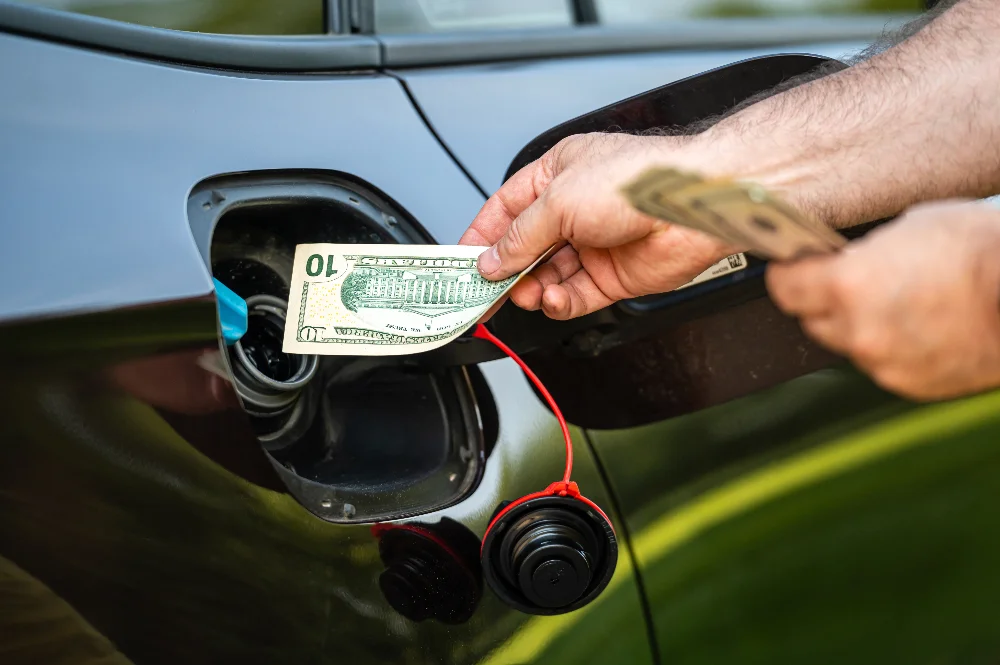 Homme qui insère des billets dans une voiture thermique plus coûteuse qu'un système électrique / solaire